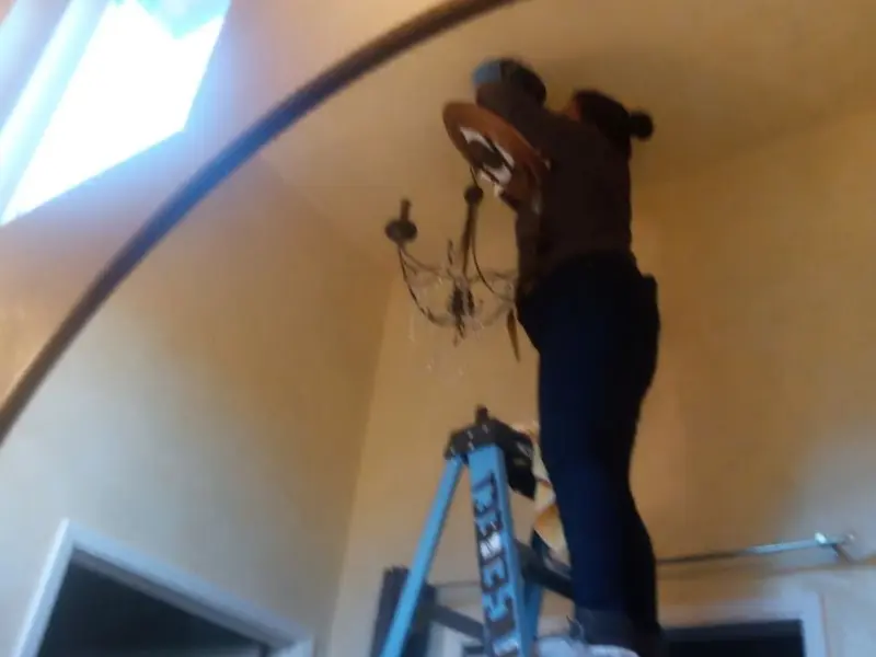Electrician installing a chandelier in a Ozark residence